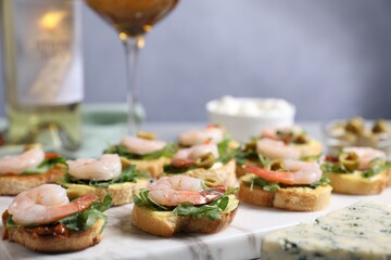 Delicious bruschettas with shrimps on light table, closeup