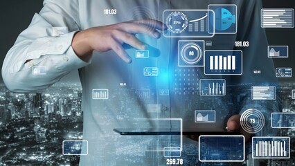 A businessman engages with a digital interface showcasing data visualizations and analytics above a tablet, with a vibrant city skyline at night enhancing the scene. Xenic