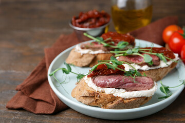 Delicious bruschettas with roast beef served on wooden table, closeup. Space for text
