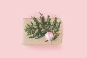 Christmas pink gift box with evergreen branches on pink background. Top view.