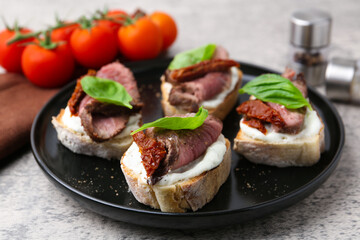 Bruschettas with roast beef served on grey table, closeup