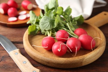 Fresh ripe radishes and knife on wooden table, closeup