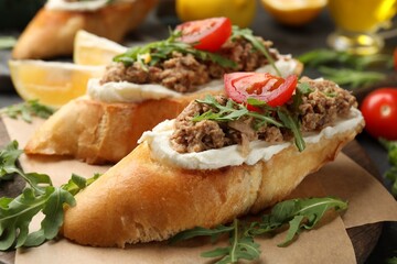 Delicious bruschettas with tuna, cream cheese and tomatoes on grey table, closeup