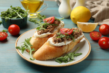 Delicious bruschettas with tuna, cream cheese and tomatoes on light blue wooden table, closeup
