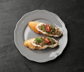 Delicious bruschettas with tuna, cream cheese and tomatoes on grey table, top view