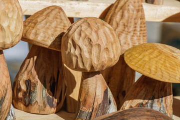 Handcrafted wooden mushrooms with natural textures displayed at artisan fair under afternoon...