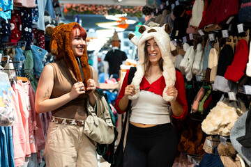 Happy friends trying on animal hats in clothing store