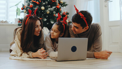 Family gathers around laptop with holiday decorations during festive celebration at home