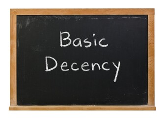 Basic Decency handwritten in white chalk on a black chalkboard isolated in a wooden frame