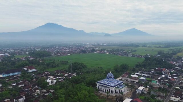 Aerial view of a beautiful mosque with Mount Kawi and Mount Arjuno in the background, Malang Regency, Indonesia