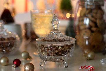 Cookie jar, tea, wine, nuts, books, lit candles and Christmas decorations on the table. Cozy Christmas hygge at home. Selective focus.
