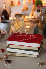 Cookie jar, tea, wine, nuts, books, lit candles and Christmas decorations on the table. Cozy Christmas hygge at home. Selective focus.