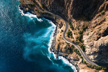 Aerial view of winding coastal road hugging cliffs above turquoise ocean