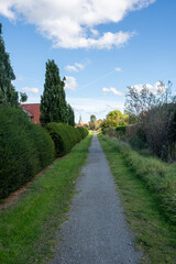 Footpath between houses with gardens, view of the church in Wremen, Germany