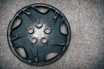 the back of a used hubcap isolated on a textured concrete background. abstract grunge automotive design element with copy space.