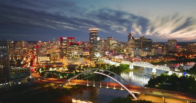 Downtown district of Nashville city in Tennessee, USA at night. Cars drive on Korean Veterans Memorial Bridge over Cumberland river. American travel destination.