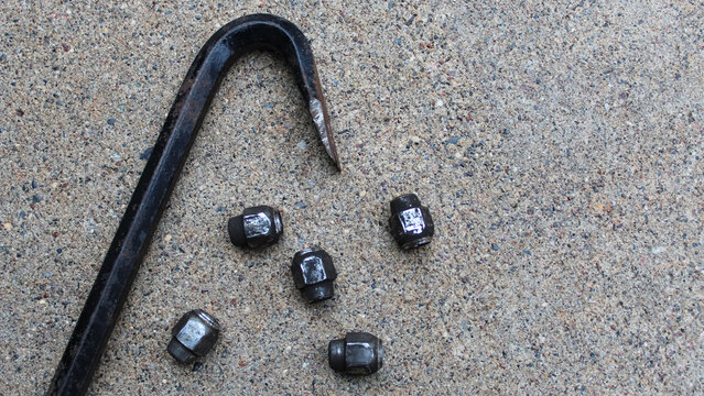 a lug wrench and several lug nuts isolated on concrete. automotive background with copy space.