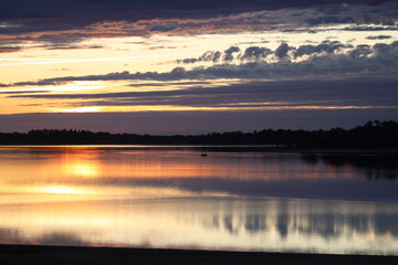 Golden sunset over tranquil lake with small boat and soft reflections