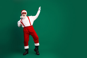 Cheerful Santa Claus sporting funky sunglass dancing joyfully in his traditional red and white costume on a green backdrop