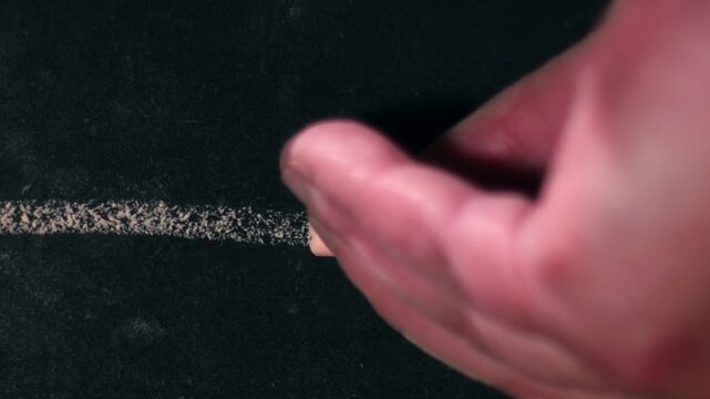 Hand drawing a straight line on chalk black board 