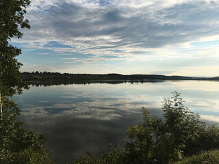 Beautiful sunset over the mirror transparent waters of lake. Travel to remote location. Save the environment, planet Earth. Clouds reflection in crystal clear water. Breathtaking panorama.