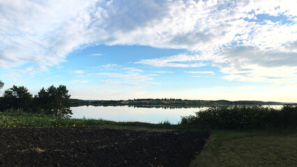 Beautiful sunset over the mirror transparent waters of lake. Travel to remote location. Save the environment, planet Earth. Clouds reflection in crystal clear water. Breathtaking panorama.