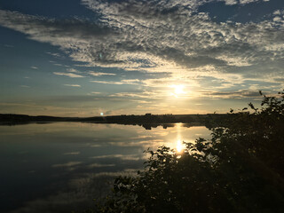 Beautiful sunset over the lake in the evening. Tranquil scenery in the countryside. Deep meditation in the nature. Magical hour of dim soft light for photography. Panoramic view of the pond.