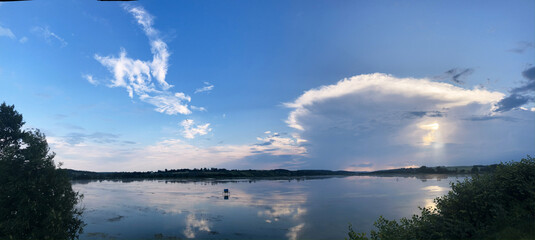 Blue and pink sunset over the mirror transparent waters of lake. Travel to remote location. Save the environment, planet Earth. Clouds reflection in crystal clear water. Breathtaking panorama.