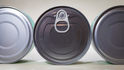 Three food tin cans lying sideways with ring‑pulls close‑up, product packaging still life