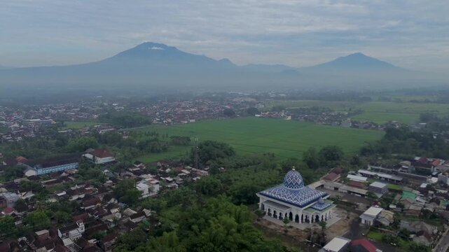 Aerial view of a beautiful mosque with Mount Kawi and Mount Arjuno in the background, Malang Regency, Indonesia