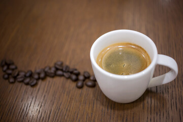 Cup of espresso coffee with coffee beans on the table, Artistic selective focus