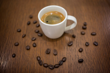 Cup of espresso coffee with coffee beans on the table, Artistic selective focus