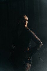 A mysterious woman stands in silhouette against a bright window, surrounded by dramatic smoke and shadows