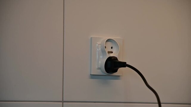 Plugging and unplugging electrical plug into power socket