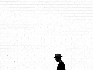Man in fedora walking past white brick wall male person