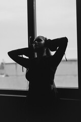 A mysterious woman stands in silhouette against a bright window, surrounded by dramatic smoke and shadows