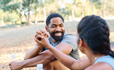 Smiling active young couple jogging exercising and having fun and gesturing high five holding water...