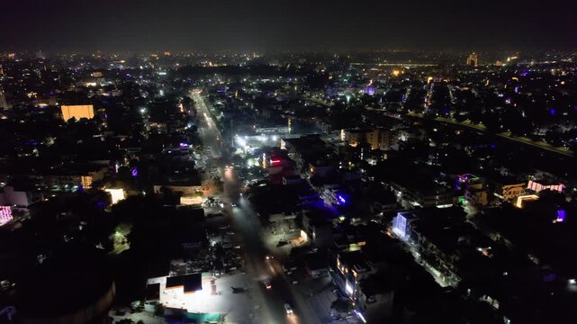 aerial drone sideways moving night shot showing cityscape of Indian city of jaipur with buildings covered in lights of diwali, makar sankranti new year and traffic moving on streets