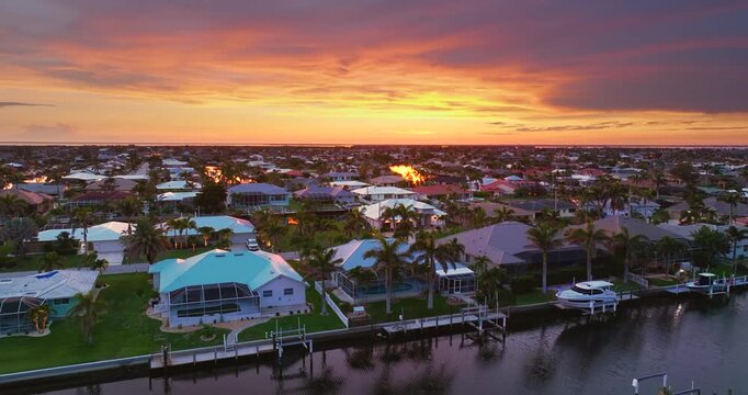 Sunset aerial view of Punta Gorda wealthy neighborhood. Expensive residential homes along canals reflect warm evening sky.