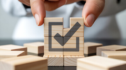 Closeup of a hand arranging wooden blocks with a check mark symbol, representing agreement, approval, confirmation, and successful completion of a task