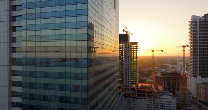 Tower cranes at high residential apartment building construction site at sunset. Real estate development in Miami urban area.