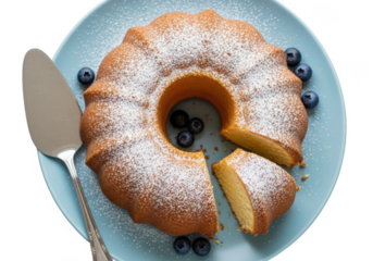 A delicious bundt cake dusted with powdered sugar and garnished with blueberries, served on a blue plate with a cake server, isolated on transparent background