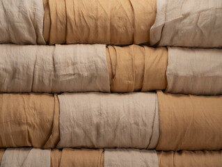 Stacked beige and tan linen fabric rolls textile