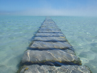 Stone path submerged in clear turquoise ocean water
