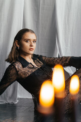 Mysterious young woman in black lace gazes intensely through candlelight, evoking elegance and gothic allure