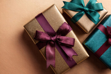 Three Metallic Gift Boxes with Ribbons on Brown Leather Surface