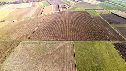 Aerial view of vast agricultural fields in varying shades of brown and green. Captured during...