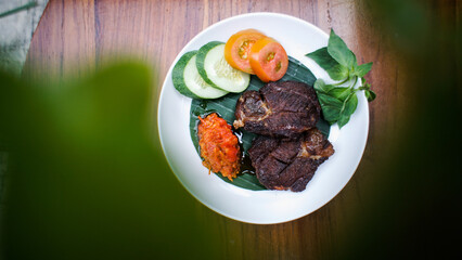 A top-down shot of a plate with fried fish, vegetables, and chili sauce.