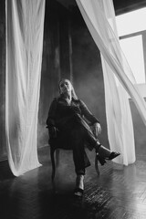 Confident woman in sheer black lace stands poised between white curtains, embodying strength, elegance, and modern gothic fashion