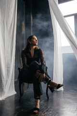 Confident woman in sheer black lace stands poised between white curtains, embodying strength, elegance, and modern gothic fashion